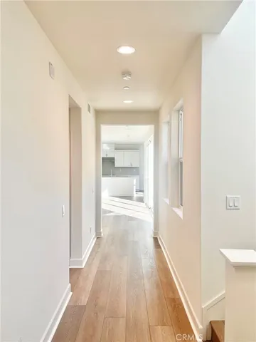 a view of a hallway with wooden floor and a bathroom