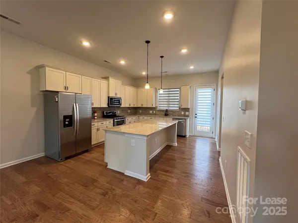 a large kitchen with stainless steel appliances kitchen island granite countertop a refrigerator and a sink