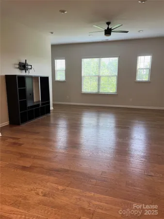 an empty room with wooden floor fireplace and windows