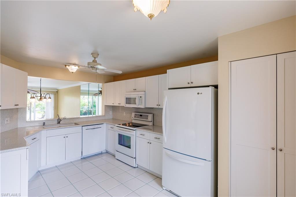 121 Gabriel Circle, Unit 1111 Naples, FL 34104 - Photo 16 of 34 a kitchen with white cabinets and white appliances