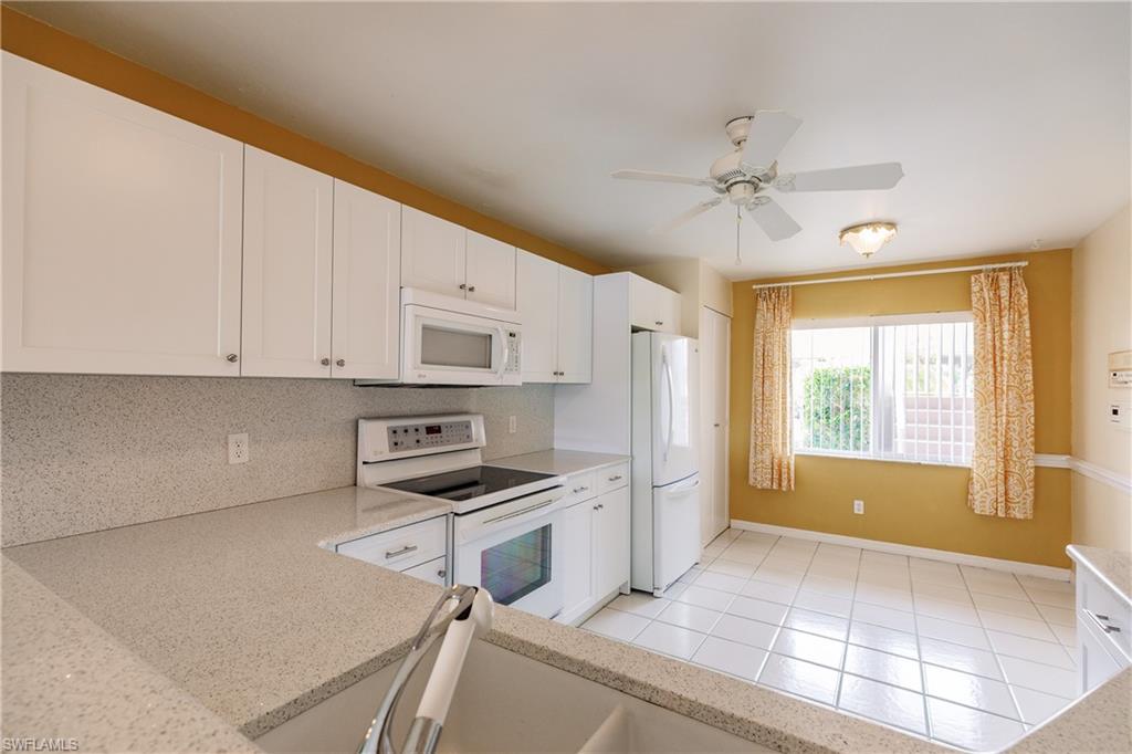 121 Gabriel Circle, Unit 1111 Naples, FL 34104 - Photo 21 of 34 a kitchen with stainless steel appliances a stove a refrigerator white cabinets and a sink