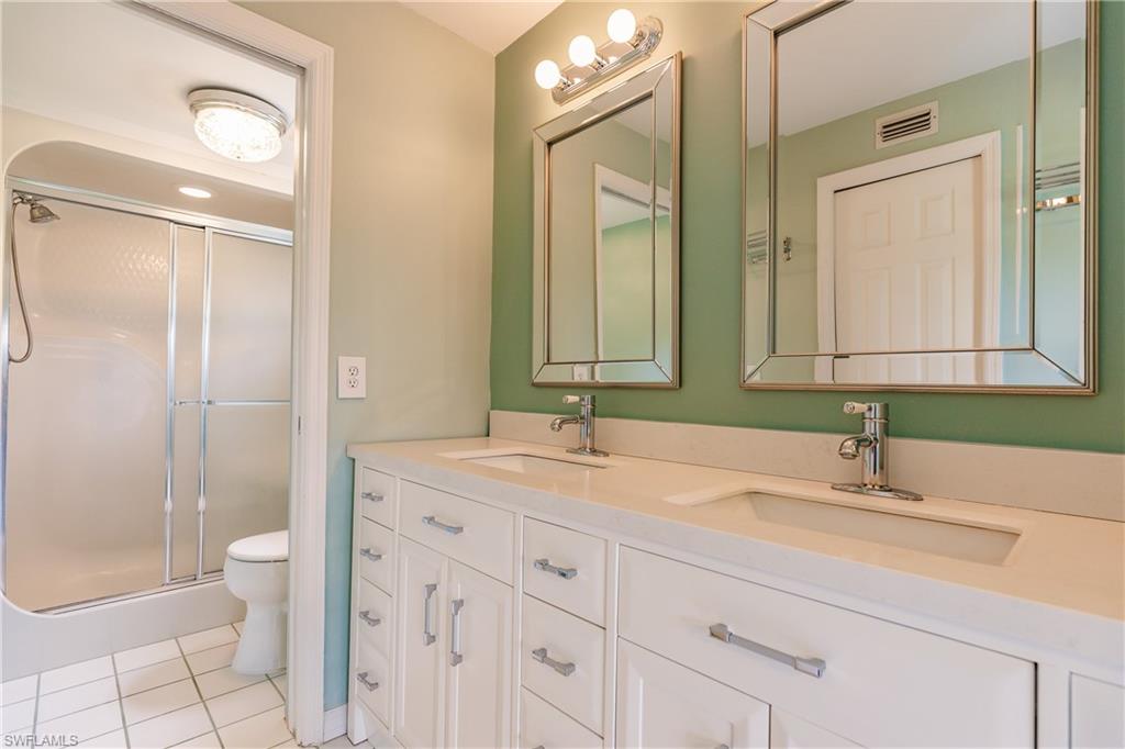 121 Gabriel Circle, Unit 1111 Naples, FL 34104 - Photo 29 of 34 a bathroom with a double vanity sink toilet mirror and shower