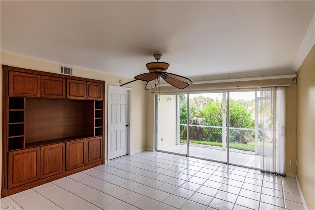 121 Gabriel Circle, Unit 1111 Naples, FL 34104 - Photo 9 of 34 a living room with flat screen tv and floor to ceiling window