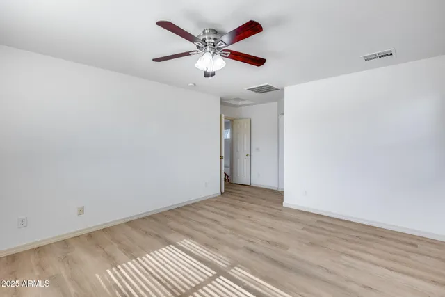 an empty room with wooden floor and ceiling fan