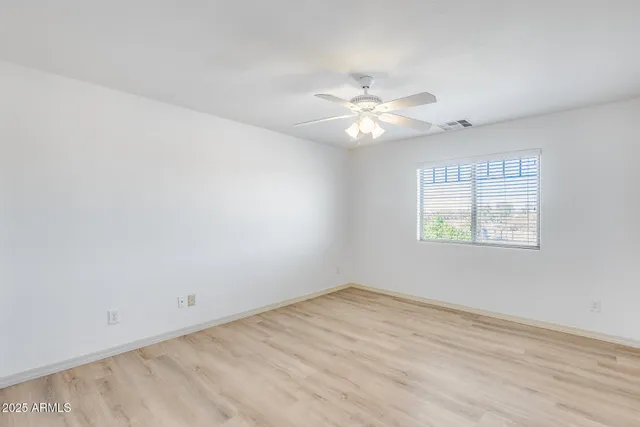 an empty room with a window and ceiling fan