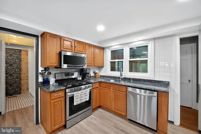 a kitchen with stainless steel appliances granite countertop sink stove top oven and refrigerator