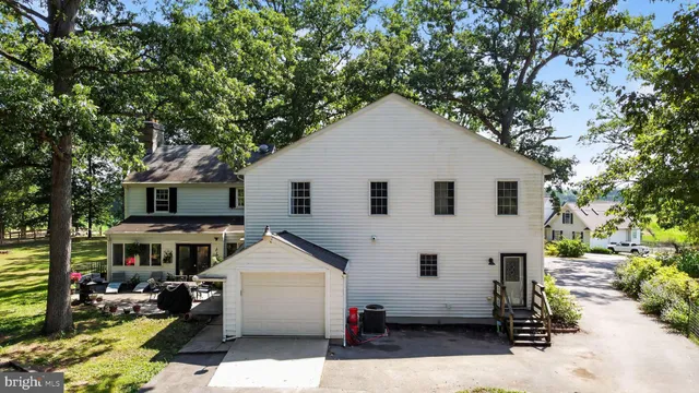 a view of a house with a yard and large trees
