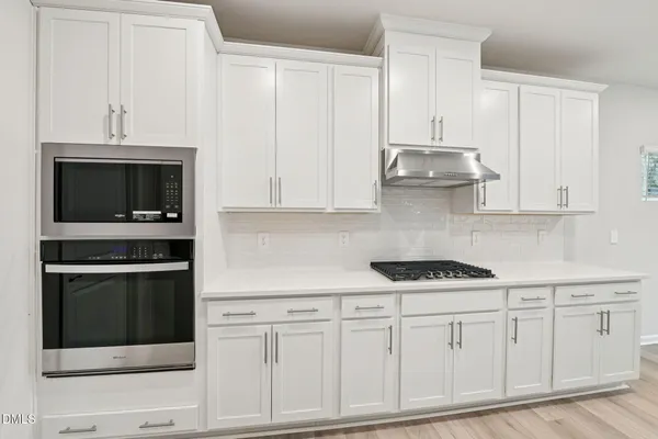 a view of a kitchen with refrigerator and white cabinets