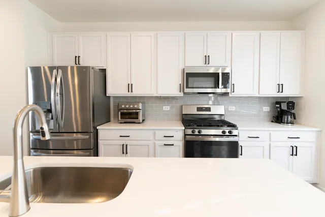 a kitchen with stainless steel appliances granite countertop a refrigerator stove top oven a sink and dishwasher