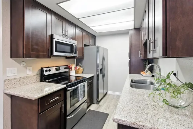 a kitchen with stainless steel appliances granite countertop a sink stove and refrigerator