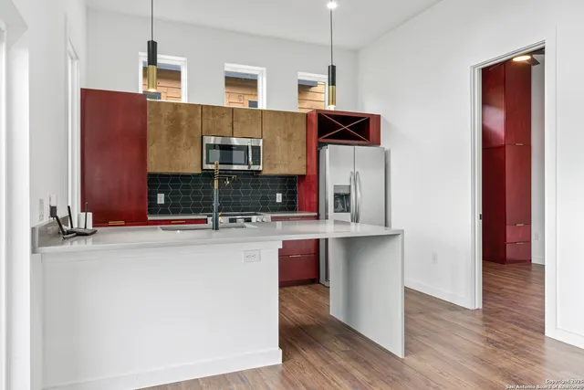 a kitchen with stainless steel appliances a sink stove and wooden floor