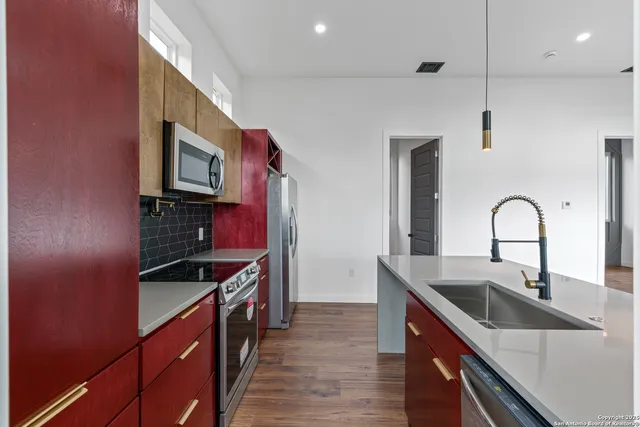 a kitchen with stainless steel appliances a sink and a stove top oven with wooden floor
