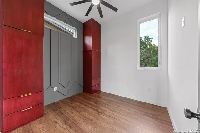 a view of empty room with wooden floor and fan