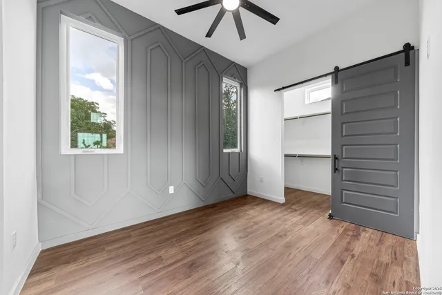 an empty room with wooden floor closet and windows