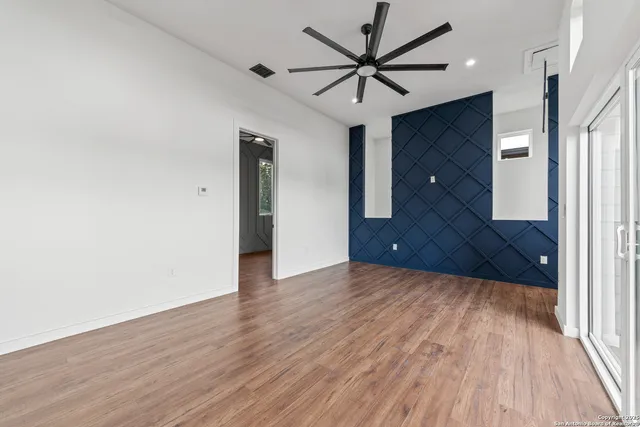 an empty room with wooden floor and a ceiling fan