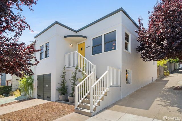 a view of a house with a small yard and a large tree