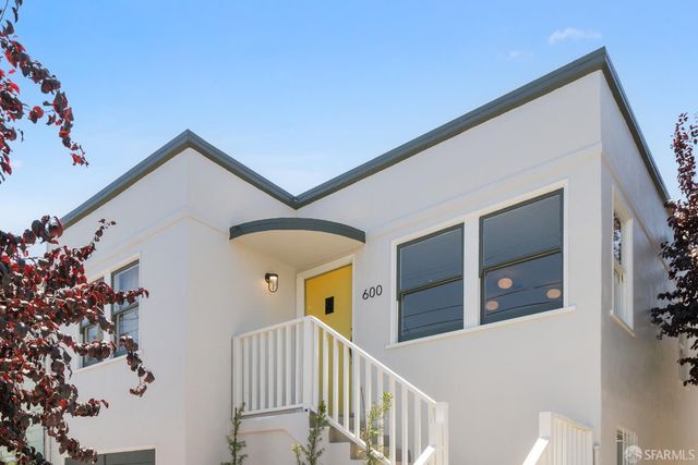 a view of a house with a small yard and potted plants