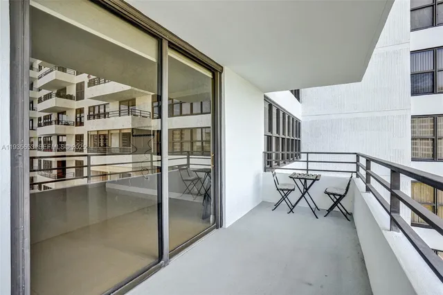 a front view of a building with lake view and tall trees