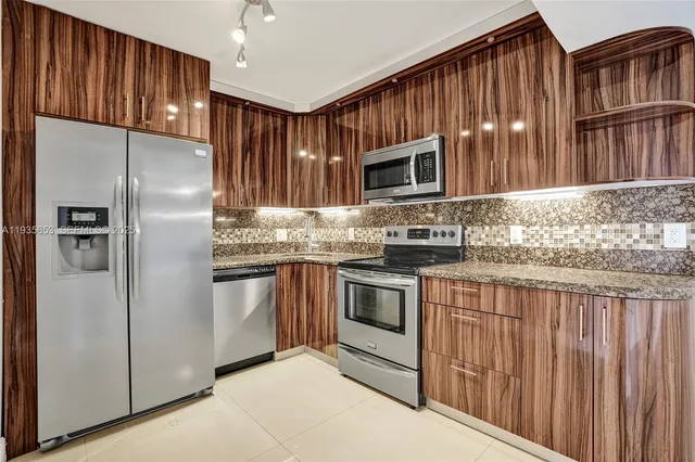 a kitchen with stainless steel appliances granite countertop a refrigerator a stove a sink and a microwave