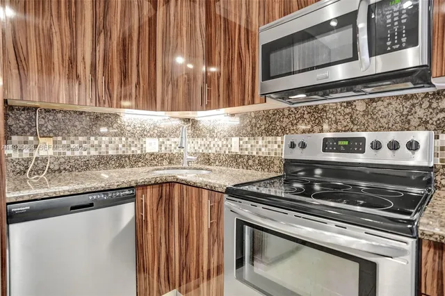a kitchen with granite countertop a stove top oven microwave and cabinets