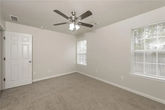 an empty room with windows and fan