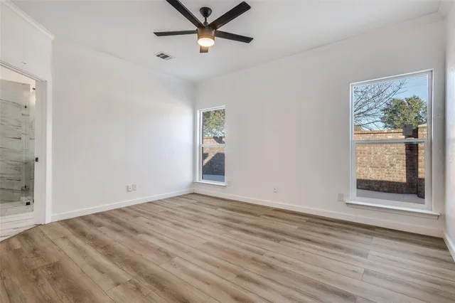 a view of an empty room with a window and wooden floor