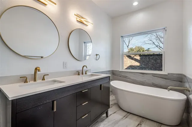 a bathroom with a tub a double vanity sink and a mirror