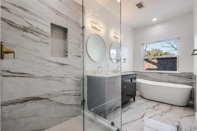 a bathroom with a double vanity sink mirror and bathtub
