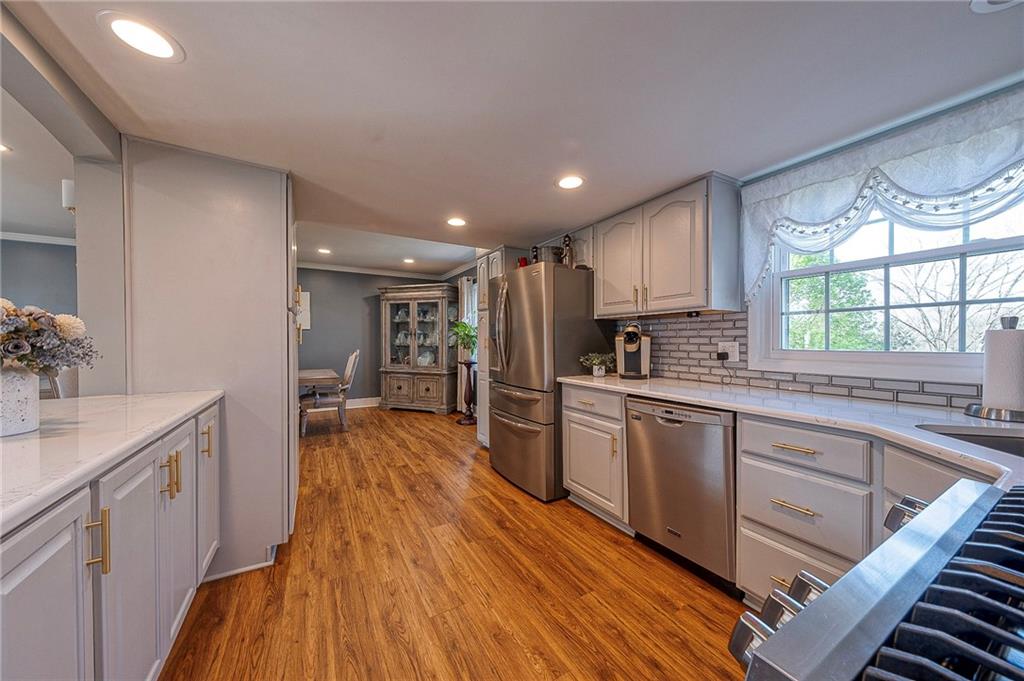 114 Truman Street Monaca, PA 15061 - Photo 11 of 30 a kitchen with wooden floors and white cabinets