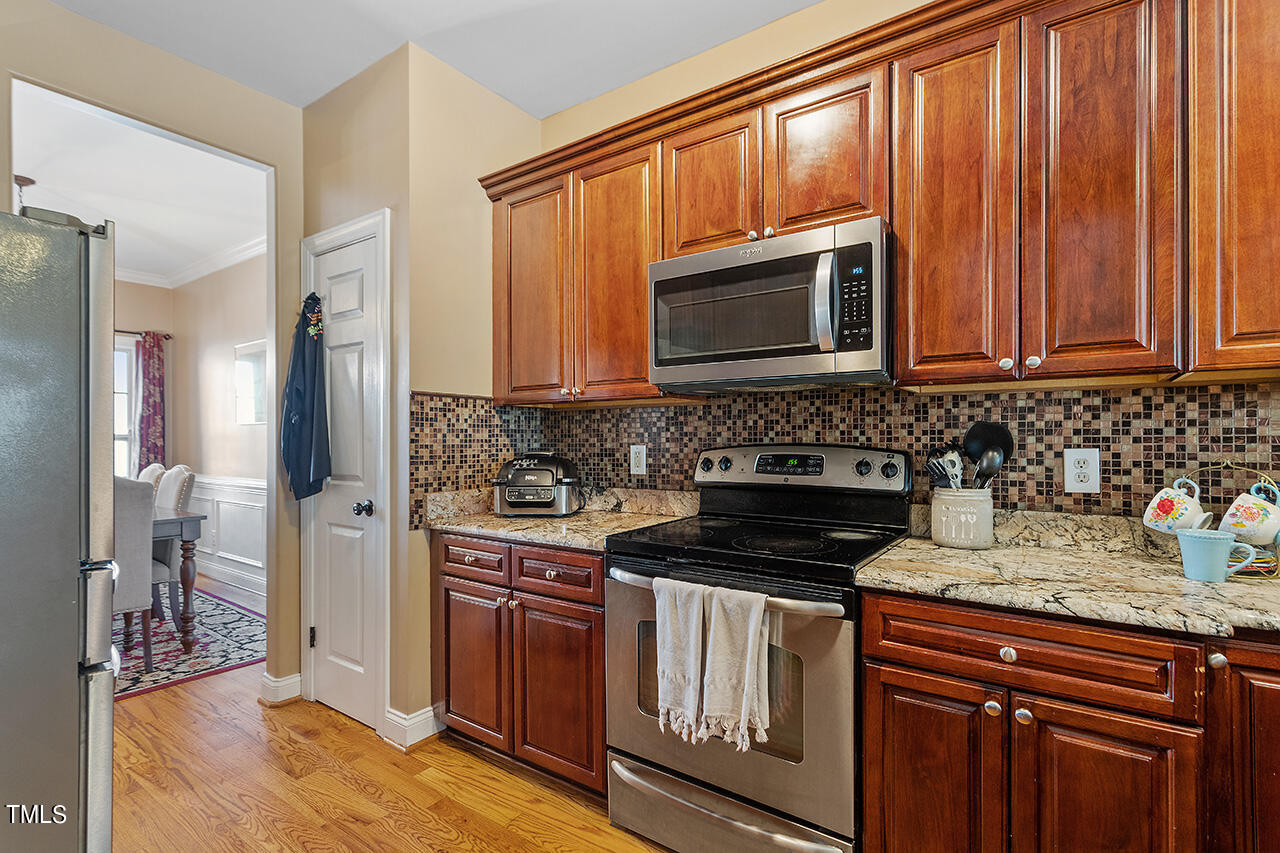 4628 Pat Reed Road Raleigh, NC 27616 - Photo 12 of 34 a kitchen with granite countertop wooden cabinets and a stove top oven