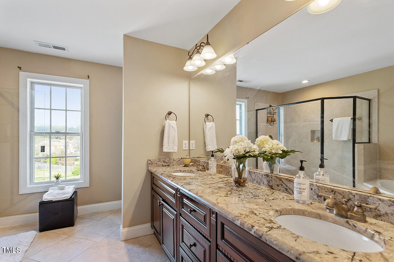 4628 Pat Reed Road Raleigh, NC 27616 - Photo 24 of 34 a bathroom with a granite countertop sink a large mirror and a bathtub