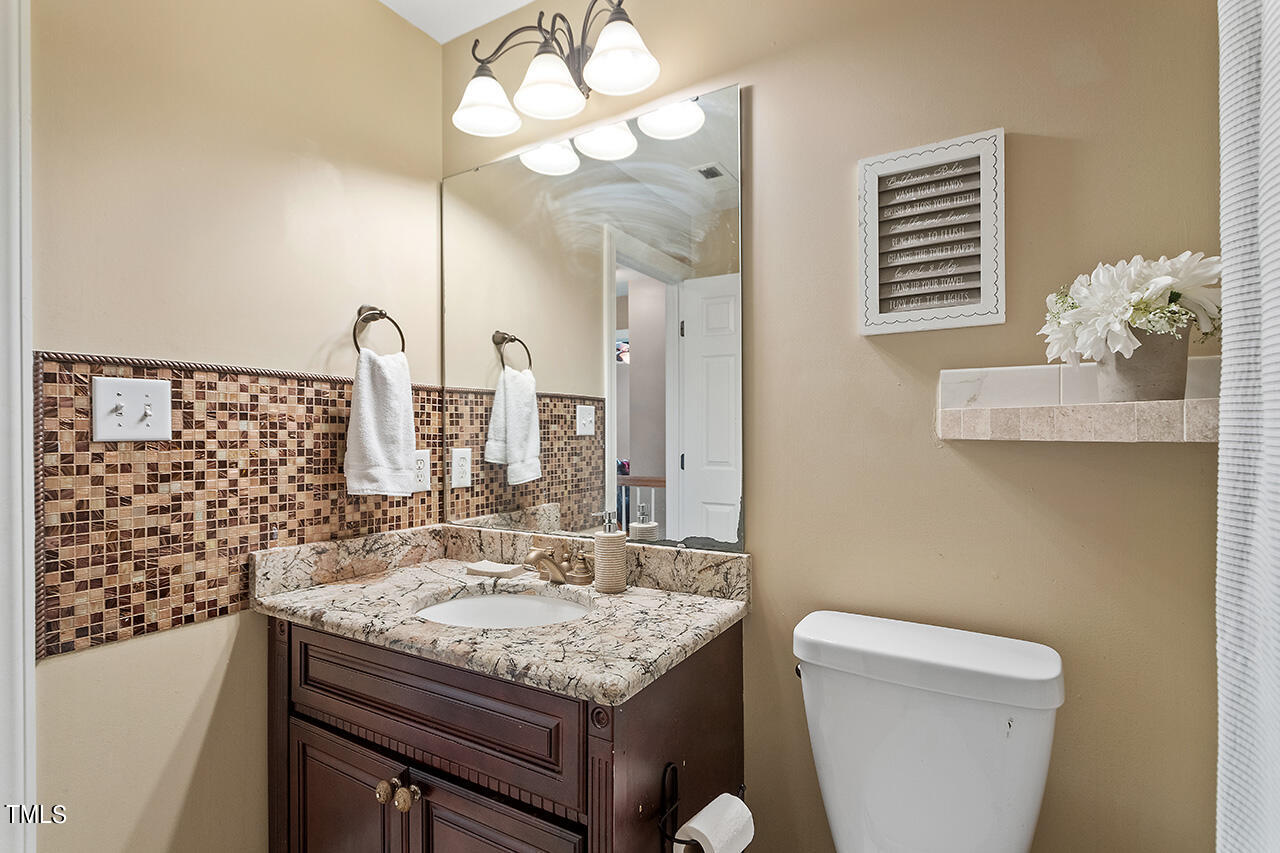 4628 Pat Reed Road Raleigh, NC 27616 - Photo 33 of 34 a bathroom with a granite countertop sink a toilet and a mirror