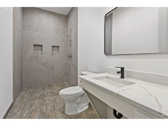 a bathroom with a granite countertop sink a toilet and a mirror