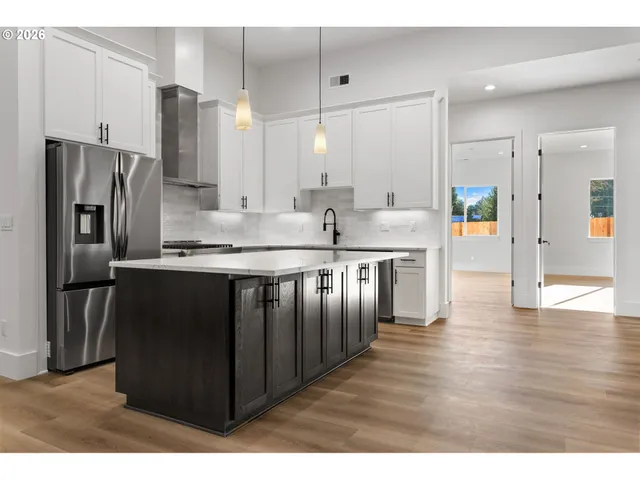 a kitchen with stainless steel appliances granite countertop a refrigerator a sink a stove and oven