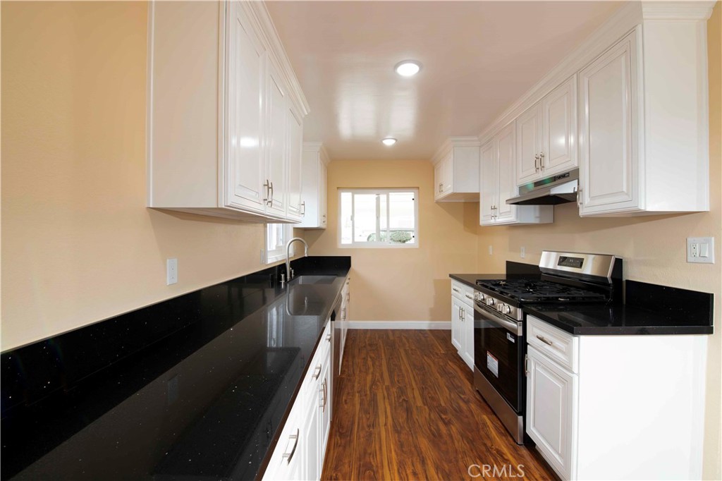 143 West 234th Place Carson, CA 90745 - Photo 24 of 46 a kitchen with granite countertop stainless steel appliances a stove a sink a refrigerator white cabinets and wooden floor