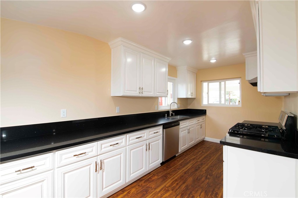 143 West 234th Place Carson, CA 90745 - Photo 25 of 46 a kitchen with granite countertop white cabinets and black appliances