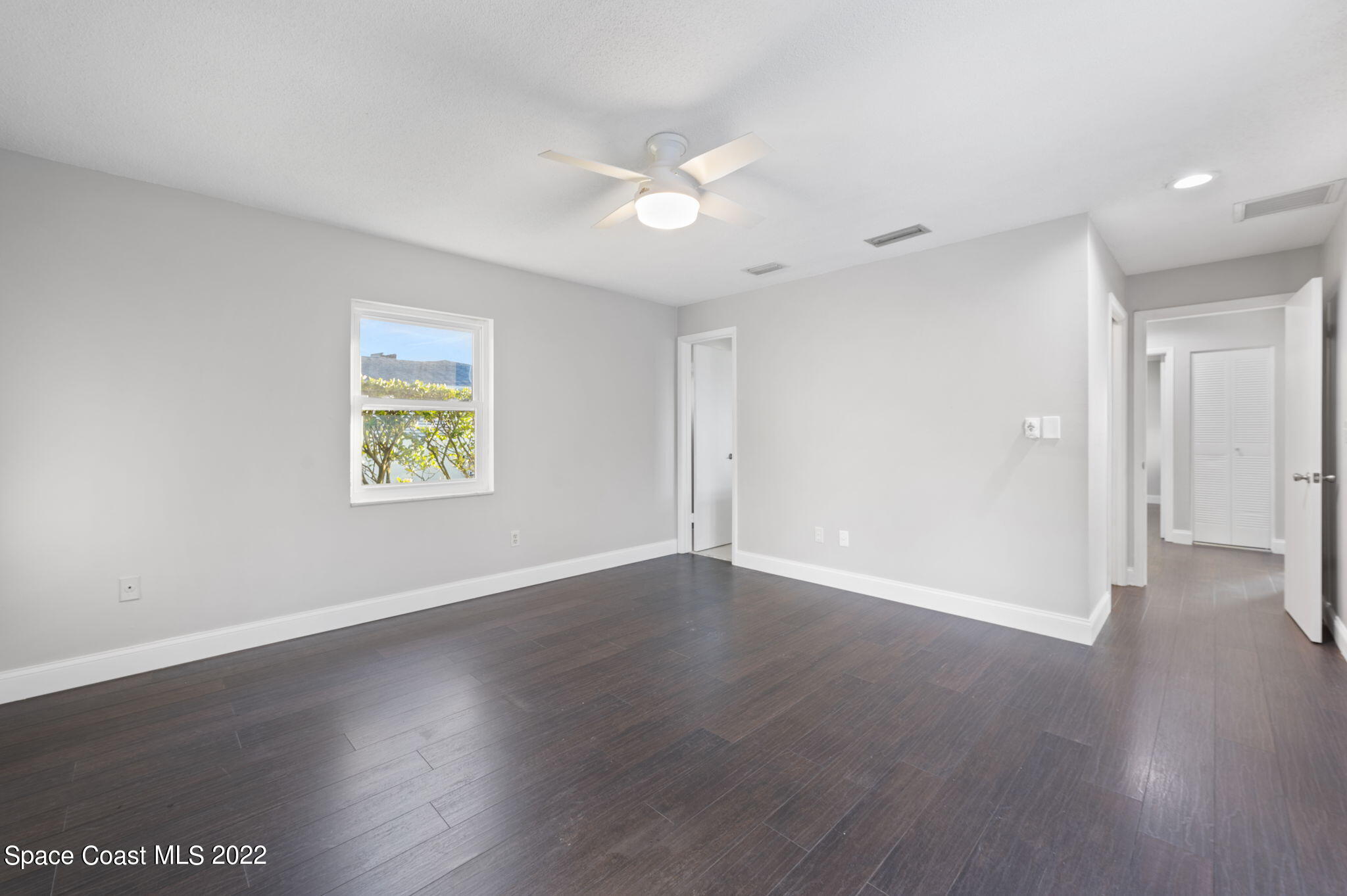 1141 Cromey Road Northeast Palm Bay, FL 32905 - Photo 13 of 27 an empty room with wooden floor and windows