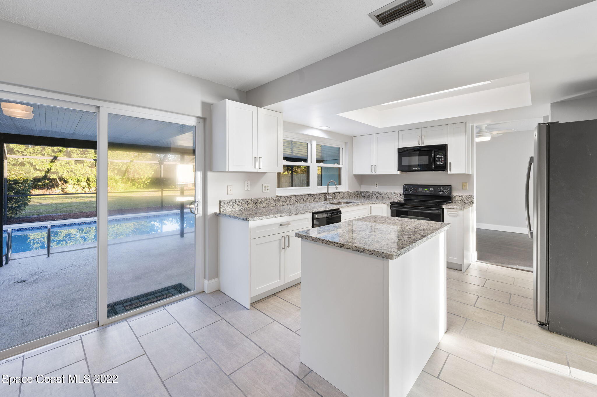 1141 Cromey Road Northeast Palm Bay, FL 32905 - Photo 2 of 27 a kitchen with a refrigerator a stove top oven and a large window