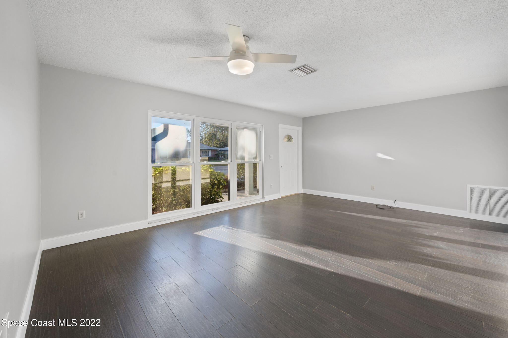 1141 Cromey Road Northeast Palm Bay, FL 32905 - Photo 8 of 27 an empty room with wooden floor and windows