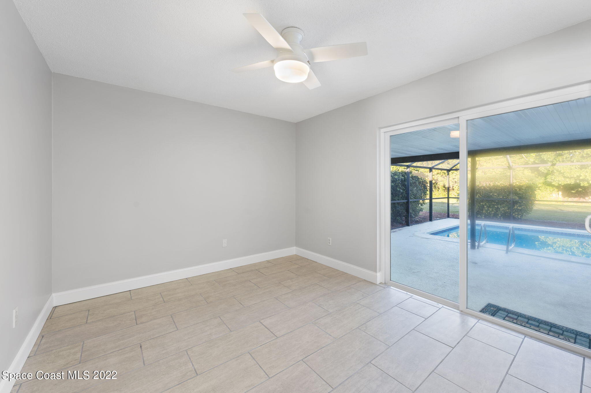 1141 Cromey Road Northeast Palm Bay, FL 32905 - Photo 10 of 27 an empty room with floor to ceiling windows and an ceiling fan