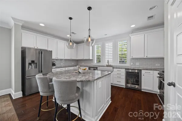 a kitchen with stainless steel appliances granite countertop a stove a refrigerator a sink a stove a dining table and chairs