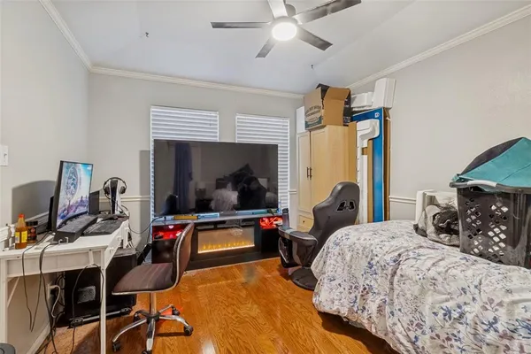 a bedroom with bed a flat tv screen and a desk