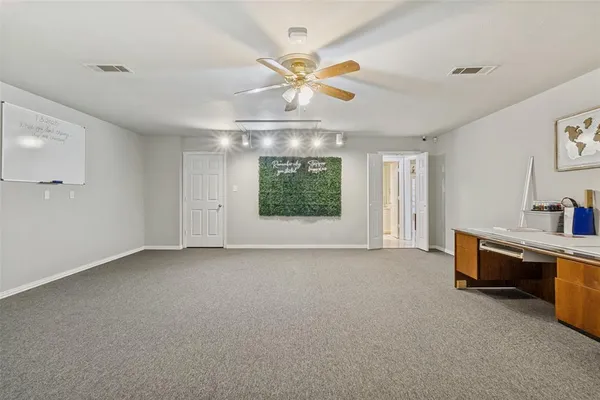 an empty room with chandelier fan and windows