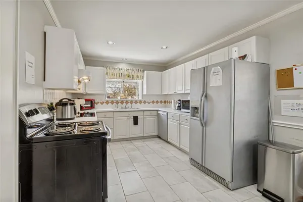 a kitchen with a sink a refrigerator and white cabinets
