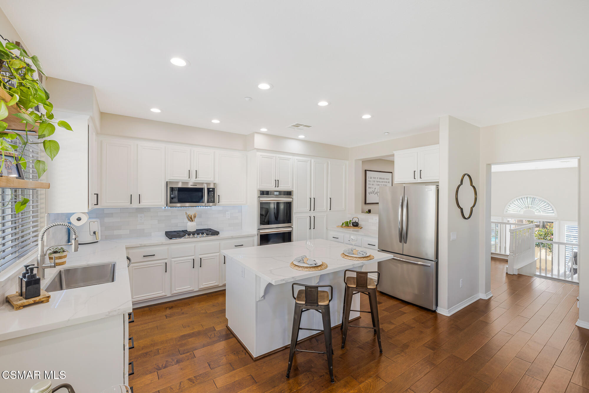 1240 Bayside Lane Oxnard, CA 93035 - Photo 19 of 51 a large white kitchen with stainless steel appliances kitchen island granite countertop a refrigerator and a stove top oven