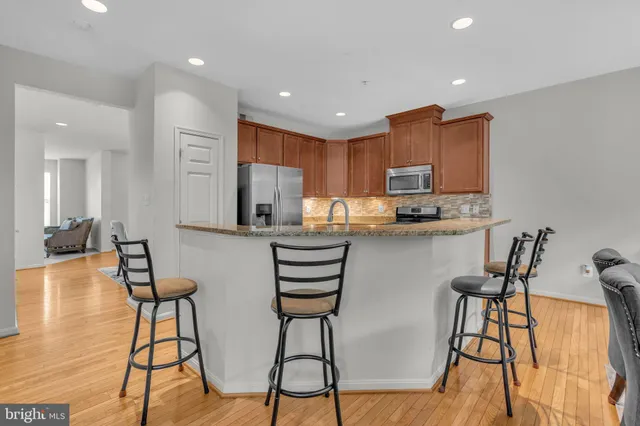 a kitchen with stainless steel appliances granite countertop a refrigerator and a stove top oven with wooden floor