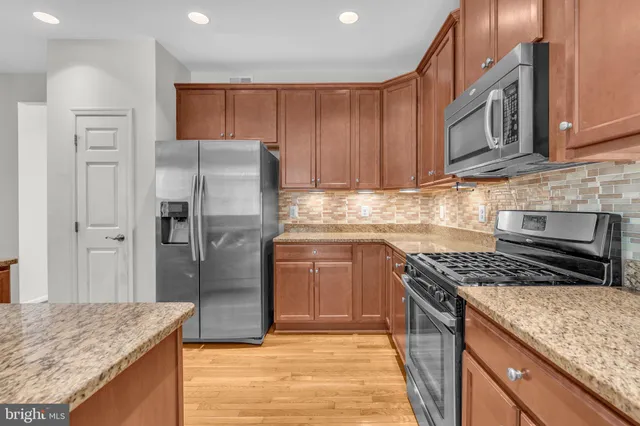a kitchen with stainless steel appliances granite countertop a refrigerator stove and oven
