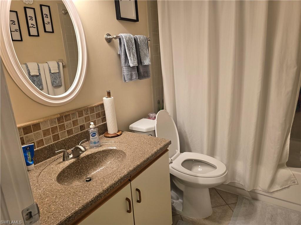 5741 Whitaker Road, Unit D203 Naples, FL 34112 - Photo 11 of 21 Guest Full bath featuring vanity, backsplash, light tile patterned flooring, and shower / bath combo with shower curtain