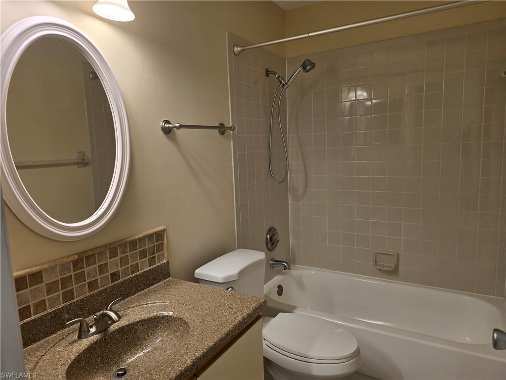 5741 Whitaker Road, Unit D203 Naples, FL 34112 - Photo 17 of 30 a bathroom with a granite countertop toilet sink and mirror