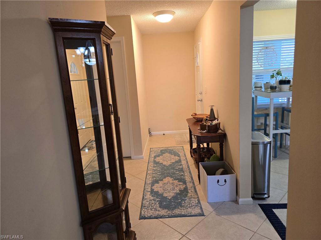 5741 Whitaker Road, Unit D203 Naples, FL 34112 - Photo 4 of 21 Entry way featuring light tile patterned floors and a textured ceiling